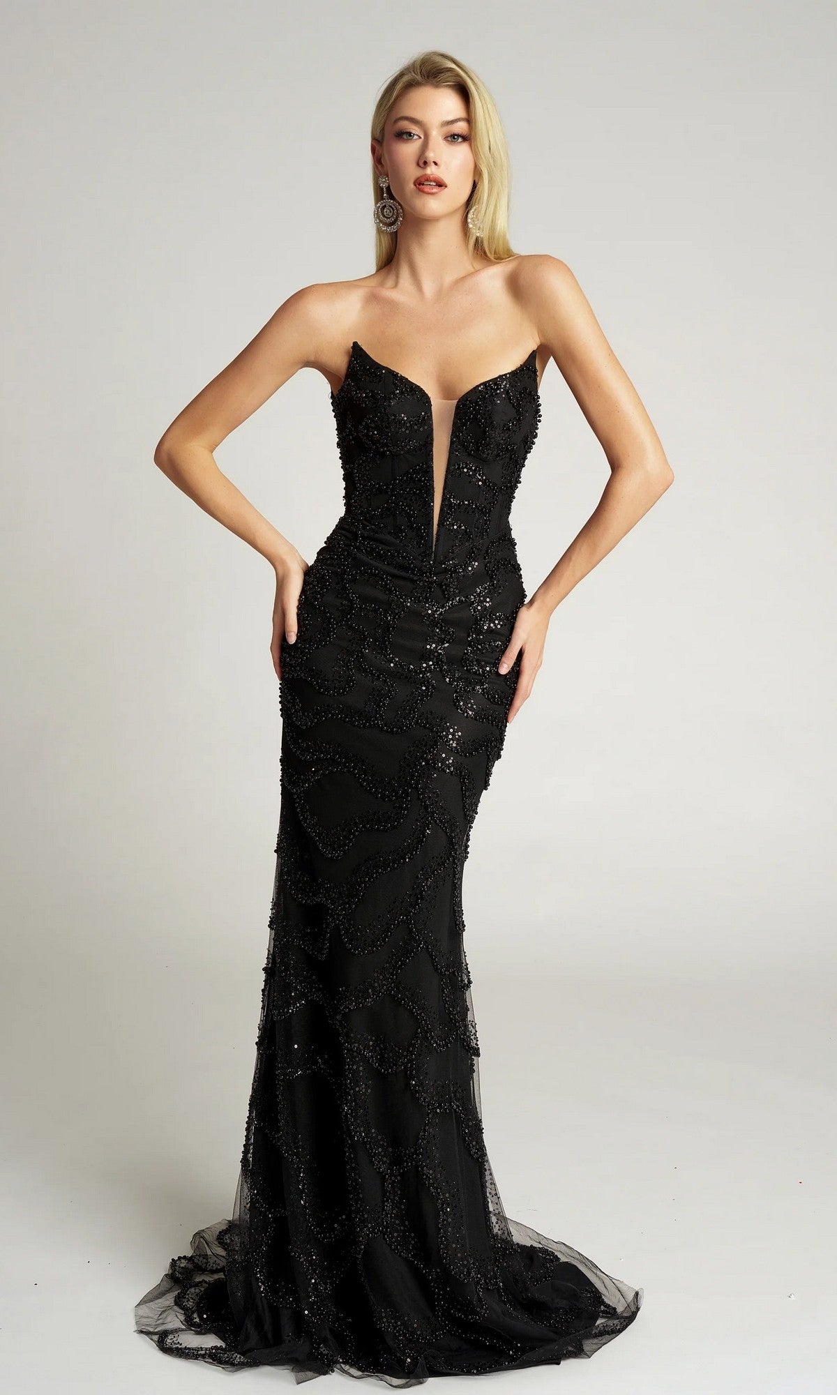A woman models the Portia and Scarlett PS26126 long formal dress, a black strapless beaded gown with a deep V neckline and floor-length silhouette, set against a plain light background.